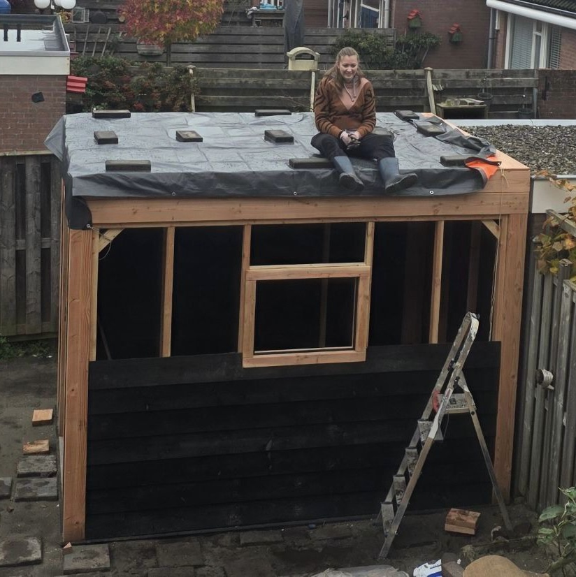 Femke op het dak van het zelfgebouwde tuinhuis